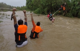 (FILE) This handout photo taken on October 11, 2021 and received on October 12 from Gonzaga Municipal Disaster Risk Reduction and Management Office (GONZAGA-MDRRMO), shows rescuers evacuating residents from their homes near a swollen river due to heavy rains brought about by Tropical Storm Kompasu in Gonzaga town, Cagayan province, north of Manila. -- Photo: Gonzaga Municupal Disaster Risk Reduction and Management Office/ AFP