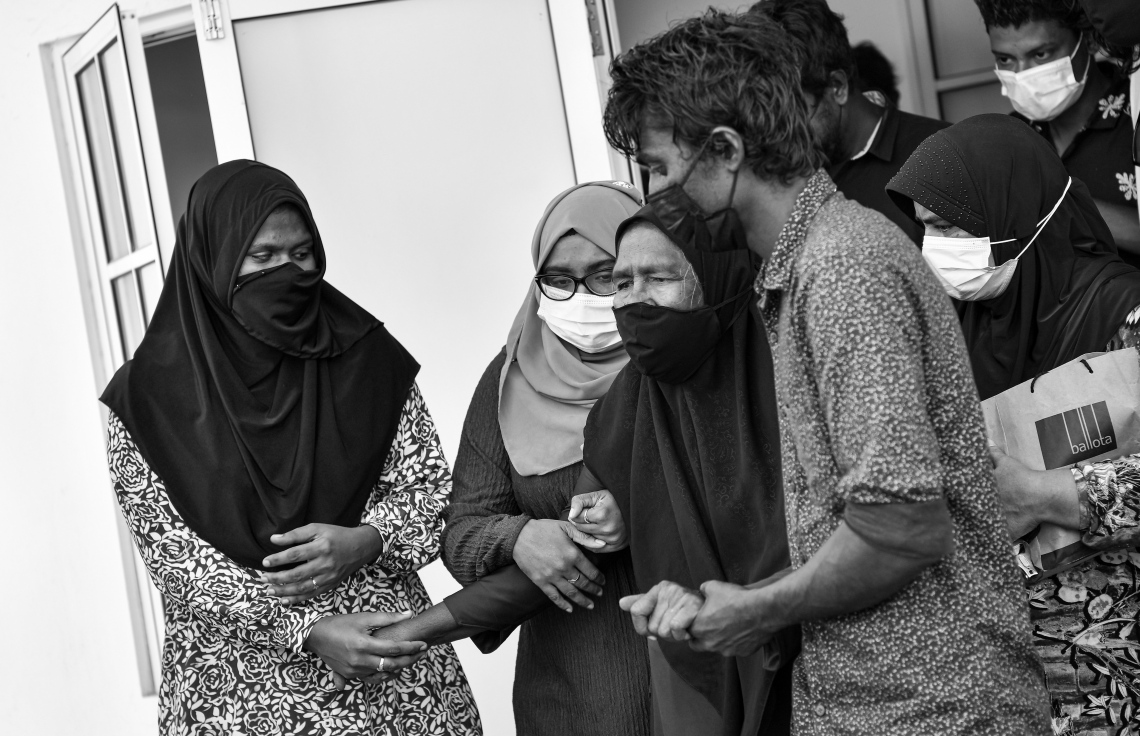 ދަނގެތި: އޮކްޓޯބަރު 15، 2021- މި ރަށުގައި އިހާނެތިކޮށް މަރާލައި އެއްލާލާފައި އޮއްވައި ފެނުނު ވިޔަފާރިވެރިޔާ މަހުމޫދު އަބޫބަކުރުގެ މޫނު ބެލުމަށް ފަހު، އޭނާގެ މަންމަ ރޯން ފެށުމުން އާއިލާގެ އެހެން ބަޔަކު ހިތްވަރު ދެނީ.-- ފޮޓޯ: ނިޝާން އަލީ/ މިހާރު