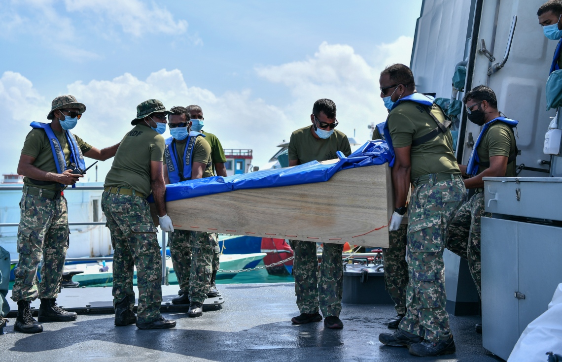 ދަނގެތި: އޮކްޓޯބަރު 15، 2021- މި ރަށުގައި އިހާނެތިކޮށް މަރާލައި އެއްލާލާފައި އޮއްވައި ފެނުނު ވިޔަފާރިވެރިޔާ މަހުމޫދު އަބޫބަކުރުގެ ހަށިގަނޑުގެ ޓެސްޓްތަކެއް ހެދުމަށް ފަހު ކޯސްޓްގާޑްގައި މިއަދު އަބުރާ ދަނގެއްޗަށް ގެންނަނީ.-- ފޮޓޯ: ނިޝާން އަލީ/ މިހާރު