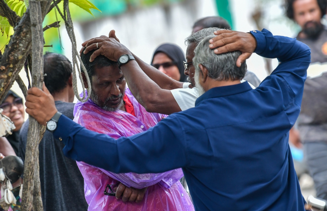 ދަނގެތި- އޮކްޓޯބަރު 16، 2021: އދ. ދަނގެތީގައި ވިޔަފާރިވެރިޔާ މަހުމޫދު އަބޫބަކުރު މަރައިލި މައްސަލައިގެ ތުހުމަތަށް ފުލުހުން ދަނގެތި ނެދުންގެ ބަލައި ފާސްކުރި ވަގުތު އެސަރަހައްދަށް އެއްވި ބައެއް މީހުން--. ފޮޓޯ: ނިޝާން އަލީ/ މިހާރު