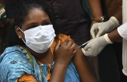 A woman reacts as a health worker inoculates her with a dose of the Covid-19 coronavirus vaccine during a door to door vaccination camp at a residential area in Chennai on October 21, 2021. -- Photo: Arun Sankar / AFP