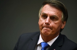 (FILES) In this file photo taken on October 22, 2021 Brazilian President Jair Bolsonaro gestures during a press conference with his Economy Minister Paulo Guedes (out of frame) at the Ministry's headquarters in Brasilia. - A Brazilian Senate commission approved a damning report on October 26, 2021 that recommends criminal charges be brought against President Jair Bolsonaro, including crimes against humanity, for his Covid policies. -- Photo: Evaristo SA / AFP