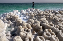 A hiker visits patterns formed by crystalized minerals in the Israeli Kibbutz Ein Gedi area at the shore of the southern part of the Dead Sea, a dried-up sea stretch which exposed and created a salt plain, on December 26, 2020. -- Photo: Menahem Kahana / AFP