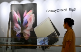 A woman walks past an advertisement for the Samsung Galaxy Z Fold3 and Flip3 smartphones at the company's Seocho building in Seoul on October 28, 2021, after South Korean tech giant Samsung Electronics posted a 28-percent jump in operating profit. -- Photo: Jung Yeon-je / AFP