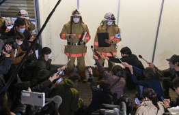 Firefighters explain the damage situation to the media at Kokuryo Station on the Keio Line in the city of Chofu in western Tokyo on October 31, 2021, after a man injured at least 10 people in a knife and fire attack on a train. -- Photo: Kazuhiro Nogi/ AFP