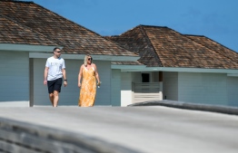 Guests walk across a string of over-water villas in Kandima Maldives--