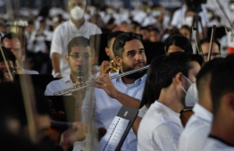 Venezuelan National Assembly deputy, Nicolas Ernesto Maduro Guerra (C), son of President Nicolas Maduro plays his flute during an attempt to enter the Guinness Book of Records for the largest orchestra in the world, with more than 12,000 musicians, at the Military Academy of the Bolivarian Army in Fuerte Tiuna Military Complex, in Caracas, on November 13, 2021. (Photo by Federico PARRA / AFP)