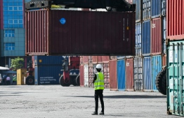 Yard supervisors inspect as imported goods in containers are unloaded at Male' Commercial Harbor site--