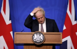 Britain's Prime Minister Boris Johnson gestures as he attends a media briefing on the latest Covid-19 update in the Downing Street briefing room, central London on November 27, 2021. - Britain will require all arriving passengers to isolate until they can show a negative PCR test against Covid-19, Prime Minister Boris Johnson said Saturday after the new Omicron strain emerged. (Photo by Hollie Adams / POOL / AFP)