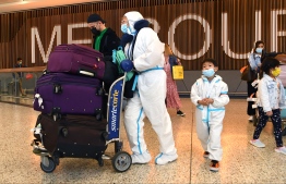 International travellers wearing personal protective equipment (PPE) arrive at Melbourne's Tullamarine Airport on November 29, 2021 as Australia records it's first cases of the Omicron variant of Covid-19. -- Photo: William West / AFP