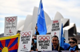 (FILES) In this file photo taken on June 23, 2021 protesters hold up placards and banners as they attend a demonstration in Sydney to call on the Australian government to boycott the 2022 Beijing Winter Olympics over China's human rights record. -- Photo Saeed Khan / AFP