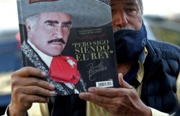 Miguel del Toro, 65, shows a book on Mexican singer Vicente Fernandez's life outside the Country 2000 hospital in Guadalajara, Mexico, on December 12, 2021. - Fernandez, the most important representative of ranchera music in Mexico, died Sunday in Guadalajara at 81, after remaining in the hospital for almost five months due to a domestic accident, his family informed. -- Photo: Ulises Ruiz / AFP