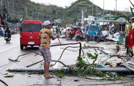 This photo taken on December 17, 2021 shows a resident removing debris caused by Super Typhoon Rai after the storm crossed over Surigao City in Surigao del Norte province. -- Photo: Erwin Mascarinas/ AFP