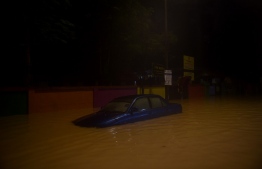 A car is seen in flood water caused by heavy rain in Kuala Lumpur early on December 19, 2021. -- Photo: Arif Kartono / AFP