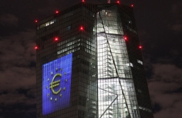 The tower of the European Central Bank (ECB) main building is pictured by night showing the illuminated euro currency symbol in Frankfurt/Main, western Germany, on December 30, 2021, during a preview of the illumination for the anniversary of the euro cash. -- Photo: Daniel Roland / AFP