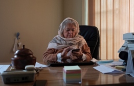 In this picture taken on December 9, 2021, Afghan women rights activist Mahbouba Seraj uses her mobile phone while sitting in her office in Kabul. - According to the United Nations, 87 percent of Afghan women have experienced some form of physical, sexual or psychological violence. -- Photo: Elise Blanchard / AFP