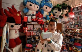 In this photo taken on December 30, 2021, Olympic superfan Zhang Wenquan shows his collection of Olympic souvenirs at home in Beijing. - Crammed on every available surface in Zhang Wenquan's crowded Beijing home is Olympic memorabilia -- from mascots and torches to flags, banners, clothes and cuddly toys. -- Photo: Jade Gao/ AFP