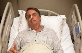 This picture obtained from the twitter official account of Brazil's President Jair Bolsonaro (@jairbolsonaro), shows Brazil's President Jair Bolsonaro posing for a picture while hospitalized due to an intestinal obstruction, in Sao Paulo, Brazil, on January 3, 2021. -- Photo: Jair Bolsonaro's official Twitter account / AFP