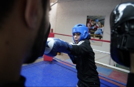 Bushra al-Hajjar, a 35-year-old Iraqi boxing instructor, is pictured during a training session with boxing coach professor Hassan Khalil, at the Islamic University in Najaf on December 14, 2021. - In Iraq's Shiite Muslim holy city of Najaf, the sight of a women's boxing hall is unusual but, like others here, the 35-year-old boxing instructor Bushra al-Hajjar is fighting deeply-ingrained taboos. -- Photo: Qassem Al-Kaabi/ AFP