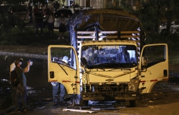 Security personnel inspect a national police truck destroyed by an explosive device in Cali, Colombia on January 8, 2022. - The explosion injured ten police officers and no deaths have been reported yet. -- Photo: Paola Mafla / AFP