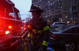 Firefighters work outside an apartment building after a deadly fire in the Bronx, on January 9, 2022, in New York. - At least 19 people have died and dozens are injured after a fire tore through a high-rise apartment building in the New York borough of the Bronx, Mayor Eric Adams said Sunday. -- Photo: Ed Jones/ AFP