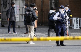 (FILE) A police officer stands guard by the entrance gate at the University of Tokyo after two students and a 72-year old were stabbed, in Tokyo on January 15, 2022: A 24 year old man in the remote town of Abu, Japan, for failure to return lump sum of money accidentally transferred to him -- Photo by JIJI PRESS / AFP