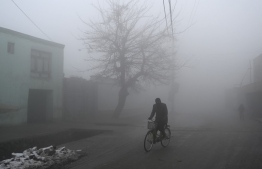 A man rides his bicycle along a road during a foggy day in Kabul on January 18, 2022. -- Photo: Wakil Kohsar / AFP
