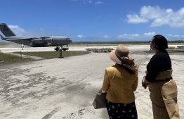 A handout photo taken and released on 20 January 2022 by the Royal Australian Air Force shows Australian High Commissioner to Tonga Rachael Moore (L) and Tongan Foreign Minister Fekitamoeloa 'Utoikamanu watching the arrival of the first Royal Australian Air Force C-17A Globemaster III aircraft from Australia delivering humanitarian assistance. -- Photo by Handout / Australian Defence Force / AFP
