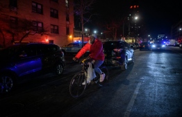 A man rides his bike on the street near the scene of a shooting in Harlem, New York on January 21, 2022. - New York's mayor called on the federal government to help "stop the flow of weapons" in the city after a police officer was killed and another wounded in a shooting. -- Photo: Ed Jones / AFP