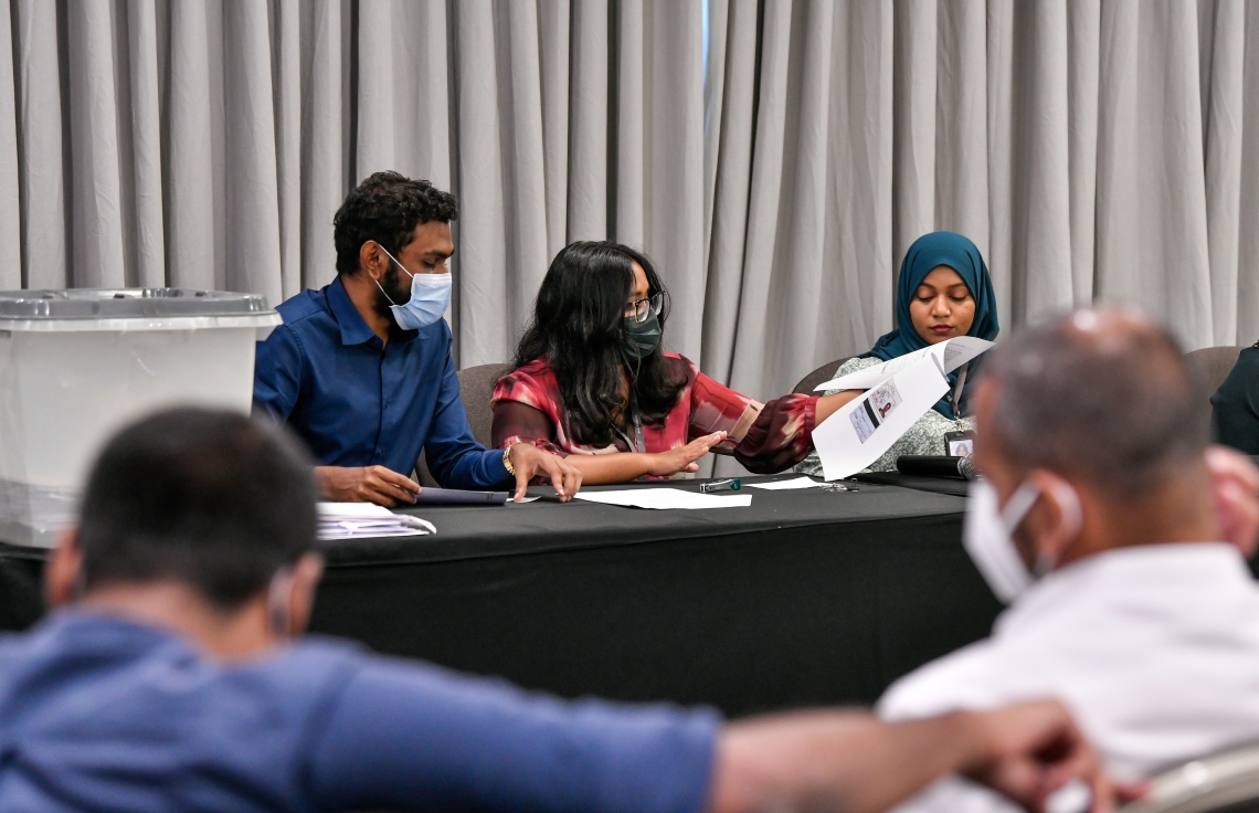 ހުޅުމާލޭގެ ދެވަނަ ފިޔަވަހީގެ ބީޗް ފްރަންޓުން ވިއްކާ ބިންތަކަށް ހުށަހެޅި ބީލަންތައް ކަނޑައި، ބީލަމުގެ އަގުތައް އެޗްޑީސީގެ އޮފިޝަލަކު އިއުލާން ކުރާއިރު އެހެން މުވައްޒަފުން އެހީތެރިވަނީ.---ފޮޓޯ: ފަޔާޒު މޫސާ/ މިހާރު