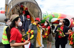 (FILES) This file photo taken on November 20, 2021 shows South Korean tourists receiving flower garlands at Phu Quoc international airport, as the Vietnamese island welcomed its first international tourists following a Covid-19 coronavirus vaccine passport scheme. - Vietnam will lift coronavirus restrictions on international passenger flights from February 15, 2022, the country's aviation authority said in a statement. -- Photo:  Nhac Nguyen/ AFP