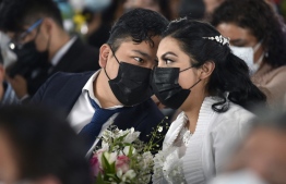 A couple is seen during a collective wedding celebration at the esplanade of the Municipal Palace of Nezahualcoyotl in Nezahualcoyotl, Mexico, on February 14, 2022. - Around 661 couples contracted civil marriages on the free collective wedding celebration event called "Por Amor a Neza 2022". -- Photo: Afredo Estrella / AFP
