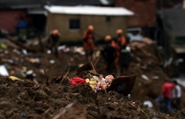 A doll lies in the rubble as members of the fire services rescue team look for survivors after a mudslide in Petropolis, Brazil on February 16, 2022. - Large scale flooding destroyed hundreds of properties and claimed at least 34 lives in the area. -- Photo: Carl De Souza / AFP