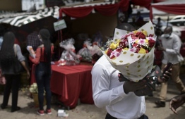 A shopper emerges from a bazaar with a wrapped arrangement of roses during Valentines day festivities in Nairobi, Kenya on February 14, 2021: US Trade Commission said they received an 80 percent increase in "romance scams" in 2021, compared to the previous year  -- Photo: Tony Karumba / AFP