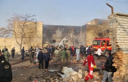 A handout picture provided by the news agency TASNIM on February 21, 2022 shows firefighters putting out a blaze at the crash site of a fighter jet in a residential area of the northwestern city of Tabriz. - An Iranian fighter jet crashed Monday in a residential area of the northwestern city of Tabriz killing three people, including two crew, state television reported. -- Photo: Tasnim News/ AFP