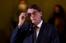 Brazilian President Jair Bolsonaro touches his glasses as he delivers a speech during the ceremony in which the new Director General of the Itaipu Bi-national Hydroelectric Power Plant, Anatalicio Risden, took office, at the Itamaraty Palace in Brasilia, on February 22, 2022.:  President Bolsonaro has urged his followers to use Telegram as the preferred messaging app as there is virtually no censorship on that platform -- Photo: Evasristo Sa / AFP