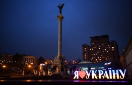 A view of the Independence Monument and a sign "I love Ukraine" in central Kyiv early on February 24, 2022. - Russian President Vladimir Putin announced a military operation in Ukraine on Thursday with explosions heard soon after across the country and its foreign minister warning a "full-scale invasion" was underway. (Photo by Daniel LEAL / AFP)