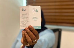 A woman shows her vaccine card issued by HPA: Police did not disclose whether they were investigating the sale of one card or multiple cards -- Photo: Mihaaru