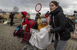 A mother and her child are seen as Ukrainian citizens arrive at the Medyka pedestrian border crossing fleeing the conflict in their country, in eastern Poland on February 27, 2022. - As Ukraine braces for a feared Russian invasion, its EU member neighbours are making preparations for a possible influx of hundreds of thousands or even millions of refugees fleeing military action. (Photo by Wojtek RADWANSKI / AFP)