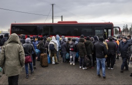 People gather to take a bus as refugees from many diffrent countries - from Africa, Middle East and India - mostly students of Ukrainian universities are seen at the Medyka pedestrian border crossing fleeing the conflict in Ukraine, in eastern Poland on February 27, 2022. - As Ukraine braces for a feared Russian invasion, its EU member neighbours are making preparations for a possible influx of hundreds of thousands or even millions of refugees fleeing military action. (Photo by Wojtek RADWANSKI / AFP)