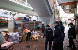 This photo taken on February 20, 2022 shows police officers (R) monitoring foreign domestic helpers (L) sheltering from the cold weather - as gatherings of more than two are now illegal due to pandemic restrictions - on their Sunday day off in Hong Kong’s Mongkok district, amid the city's worst-ever coronavirus outbreak. Few have suffered more during Hong Kong's pandemic restrictions than the hundreds of thousands of women from the Philippines and Indonesia who work as domestic helpers, and as the city reels under its most severe coronavirus wave to date, many are now at breaking point.
Bertha WANG / AFP
