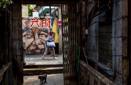 In this photo taken on February 10, 2022, a woman walks through an alley in the Talad Noi neighbourhood of Bangkok. - A 200-year-old Chinese mansion in Bangkok's heart isn't an obvious place for a scuba school, but in a city relentlessly demolishing its architectural heritage the business is helping preserve the historic home. -- Photo: Jack Taylor / AFP