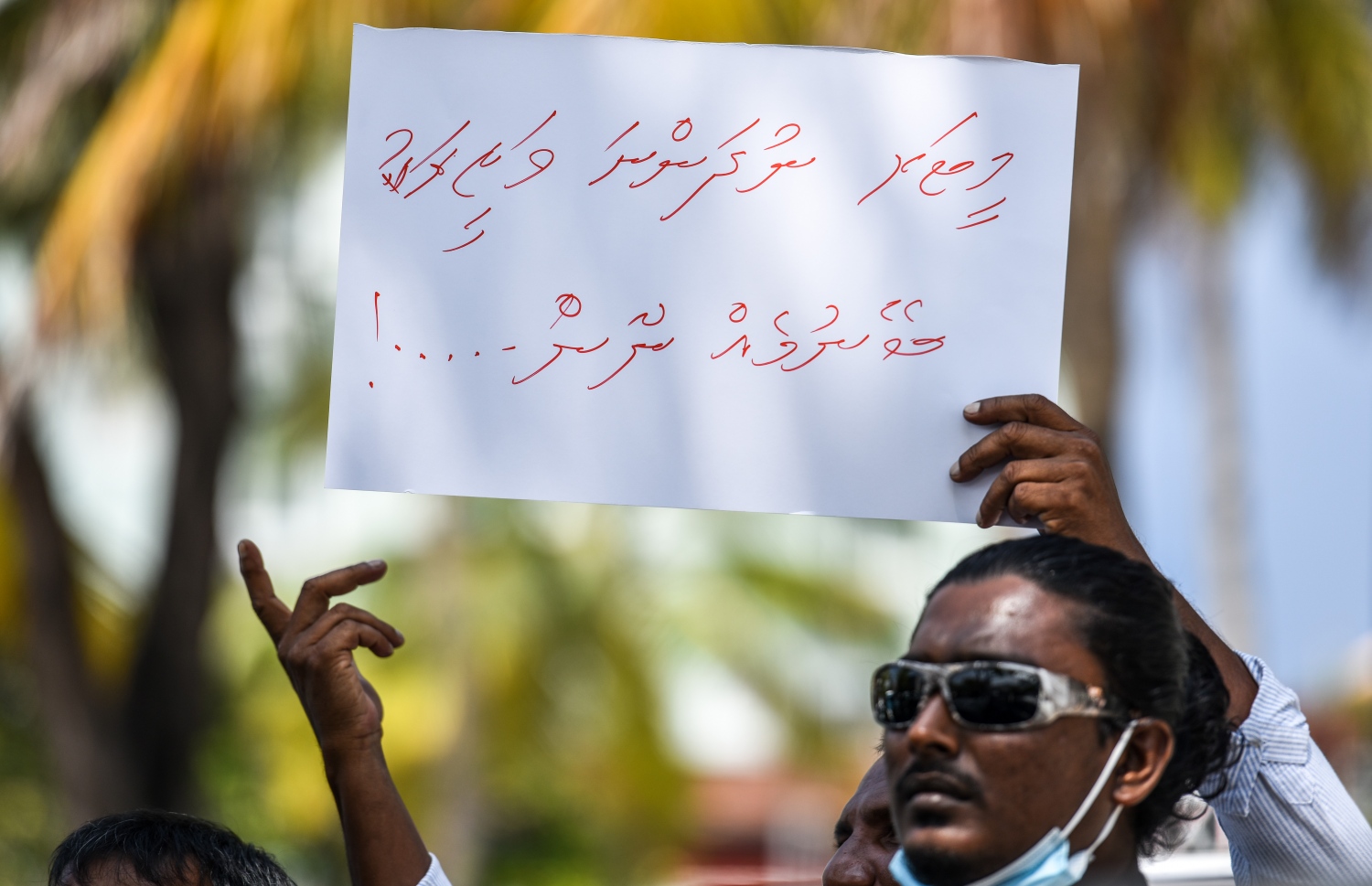 ޓެކްސީ ދަތުރުތައް ހުއްޓާލުމަށް ފަހު ޑްރައިވަރުން ބޭއްވި އިހުތިޖާޖުގައި ޑްރައިވަރަކު ޕޯސްޓަރެއް ހިފައިގެން- ފޮޓޯ: ފަޔާޒު މޫސާ/ މިހާރު