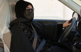 Saudi taxi driver Fahda Fahd sits in her car in the capital Riyadh, on February 8, 2022 - Like other Saudi women, Fahda Fahd couldn't legally drive until 2018, but her lime-green Kia is now a route to extra cash as living costs soar in the conservative kingdom. -- Photo: Fayez Nureldine / AFP