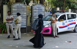A woman wearing a veil walks past police guarding outside a school in Bangalore on March 15, 2022, after an Indian court upheld a local ban on the hijab in classrooms. -- Photo: Manjunath Kiran / AFP