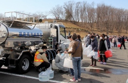 Residents queue to fill containers with water from a tanker truck in Minamisoma, Fukushima prefecture on March 17, 2022 after the water was cut off following a 7.3-magnitude quake jolted east Japan the night before. -- Photo: JIJI PRESS / AFP