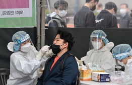A medical worker (L) takes a nasal swab sample from a man at a Covid-19 coronavirus testing centre in Seoul on March 17, 2022, after South Korea's daily infections rose sharply to hit a new high of over 600,000. -- Photo: Jung Yeon-je / AFP