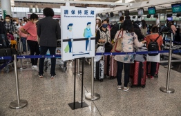 People wait in a queue to check-in for their flight at Hong Kong International Airport in Hong Kong on March 21, 2022. --Photo: Dale De La Rey / AFP