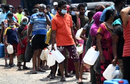 People stand in a queue to buy kerosene oil for home use at a petrol station in Colombo on March 17, 2022. -- Photo: Ishara S. Kodikara / AFP