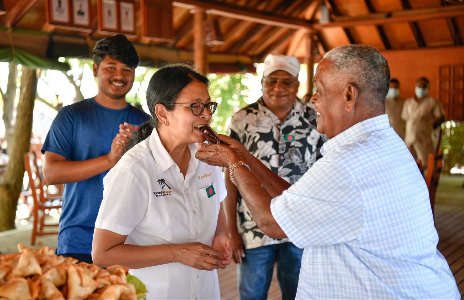 ބަންގްލަދޭޝްގެ މިނިވަން ދުވަސް، ކުރެއްދޫގައި ފާހަގަ ކުރުމަށް އެ ރިސޯޓްގެ މުވައްޒަފުންނާ އެކު، އުއްޗު ކޭކެއް ފަޅުއްވައި ދެއްވުމަށް ފަހު މުވައްޒަފެއްގެ އަނގައިގައި ކޭކު ލައްވަނީ. -- ފޮޓޯ: ނިޝާން އަލީ | މިހާރު